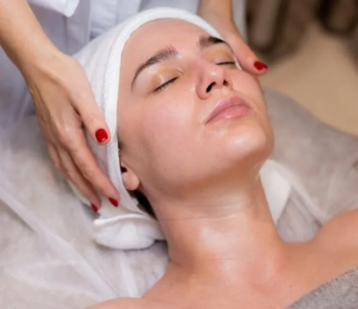 Client relaxing during a facial with a towel wrapped around her hair