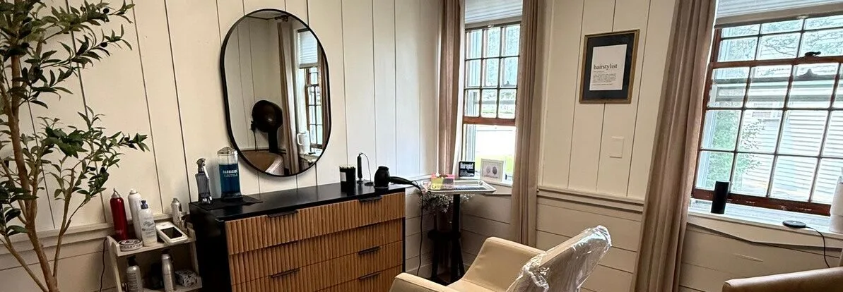 Salon interior with oval mirror, styling station and windows